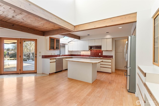 kitchen with light hardwood / wood-style flooring, appliances with stainless steel finishes, vaulted ceiling with beams, a center island, and white cabinets