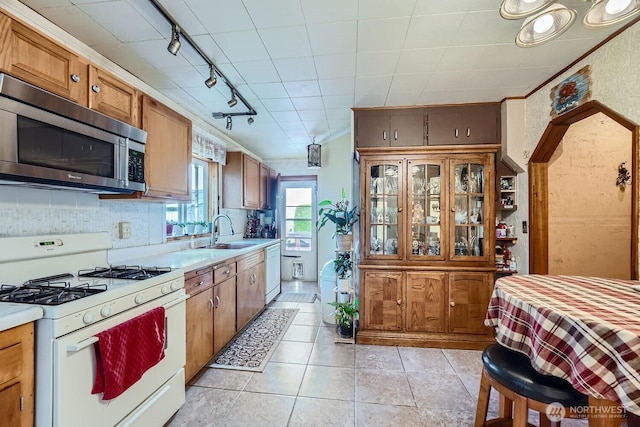 kitchen with light tile patterned flooring, sink, crown molding, white appliances, and decorative backsplash