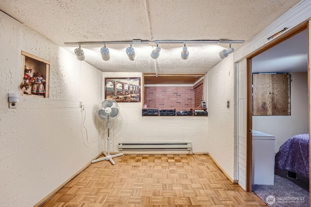 interior space with rail lighting, parquet flooring, a baseboard heating unit, and a textured ceiling