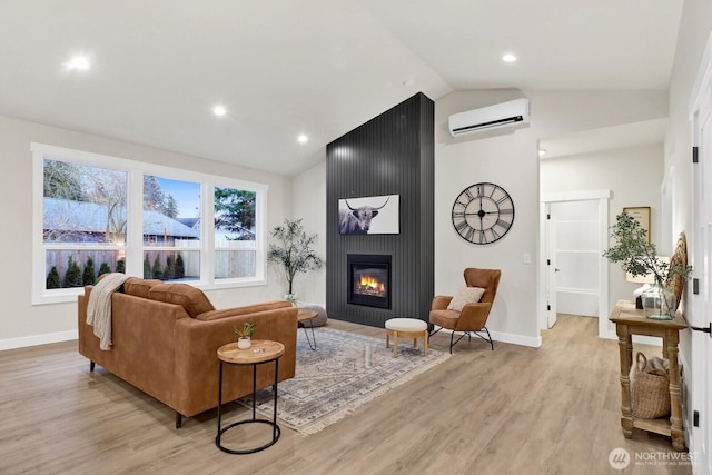 living room with vaulted ceiling, an AC wall unit, a fireplace, and light hardwood / wood-style flooring