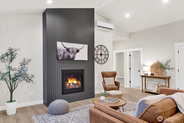 living room with vaulted ceiling, a wall mounted air conditioner, a fireplace, and light hardwood / wood-style floors