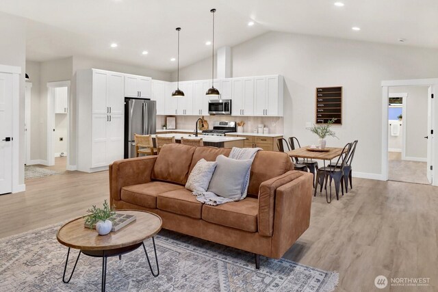 living room with high vaulted ceiling and light wood-type flooring