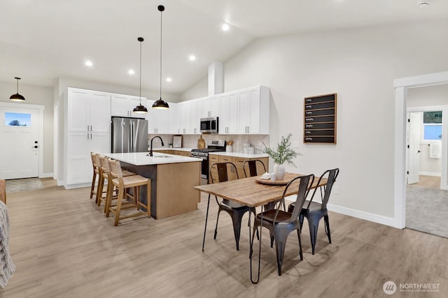 dining room featuring high vaulted ceiling, light hardwood / wood-style floors, and sink