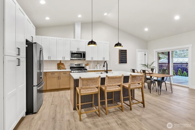 kitchen featuring sink, appliances with stainless steel finishes, white cabinetry, an island with sink, and decorative light fixtures