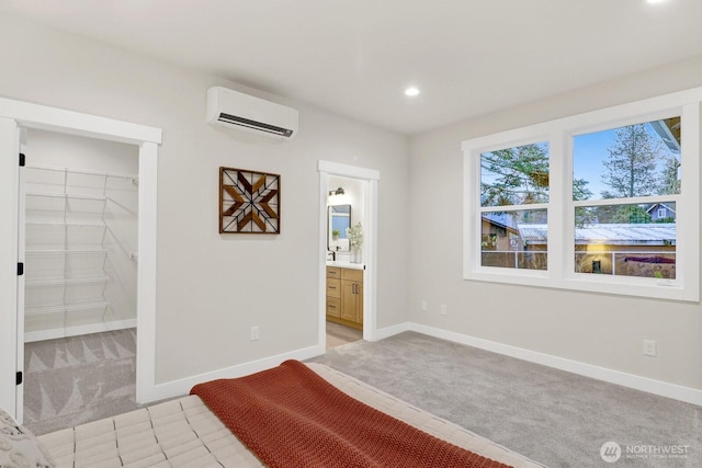 unfurnished bedroom featuring a wall mounted air conditioner, a spacious closet, ensuite bath, and light colored carpet