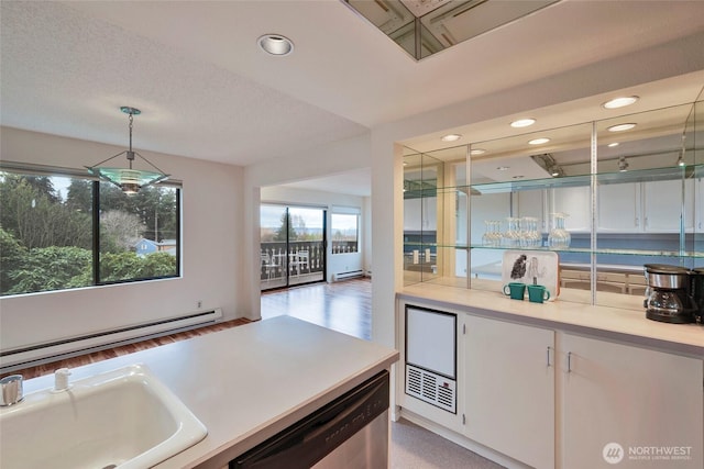 kitchen with light countertops, stainless steel dishwasher, hanging light fixtures, white cabinetry, and a baseboard radiator