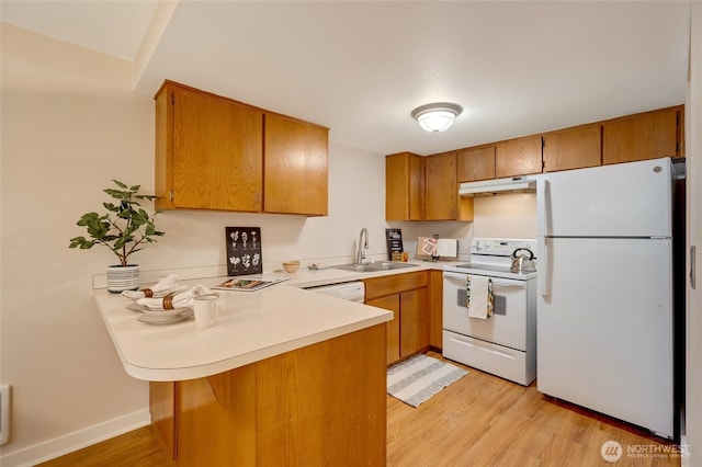 kitchen featuring sink, white appliances, kitchen peninsula, and light hardwood / wood-style floors