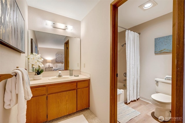 full bathroom with hardwood / wood-style flooring, vanity, shower / tub combo with curtain, and toilet