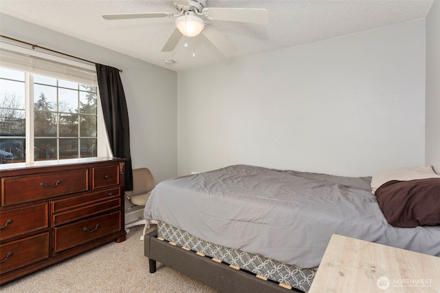 bedroom with ceiling fan, light carpet, and a textured ceiling