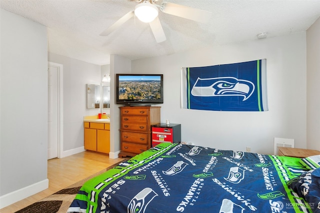 bedroom featuring ceiling fan, wood-type flooring, ensuite bathroom, and a textured ceiling