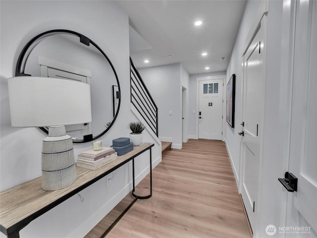 corridor featuring baseboards, stairway, recessed lighting, and light wood-style floors