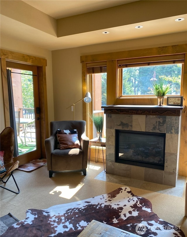carpeted living room with a healthy amount of sunlight and a tiled fireplace