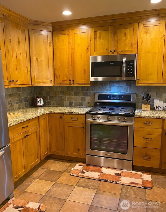 kitchen with light stone countertops, backsplash, and stainless steel appliances