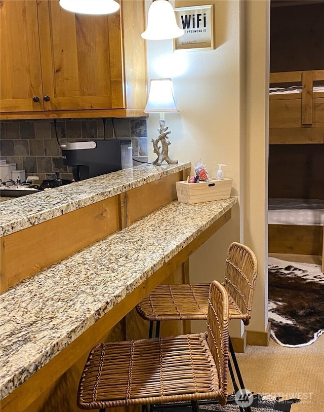 kitchen featuring tasteful backsplash, light stone countertops, and carpet