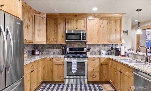 kitchen featuring decorative light fixtures, sink, backsplash, stainless steel appliances, and light stone countertops