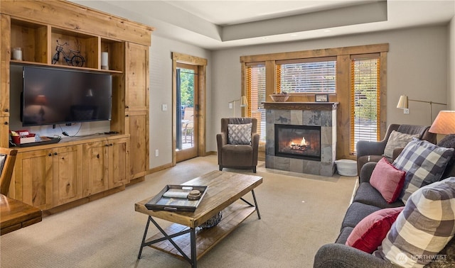 carpeted living room featuring a raised ceiling and a tile fireplace