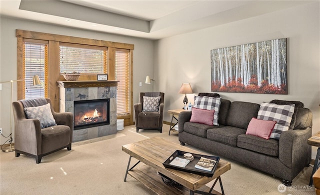 living room with a raised ceiling, a premium fireplace, and light carpet