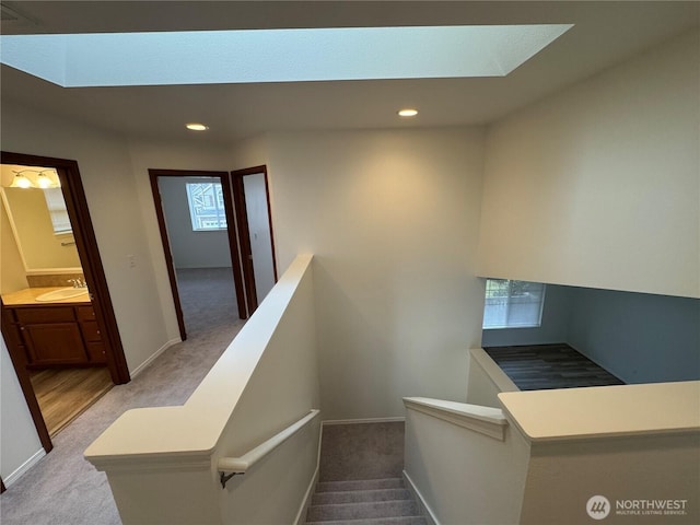 staircase with sink, a skylight, and carpet flooring