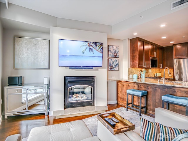 living room with dark wood-style floors, recessed lighting, visible vents, a glass covered fireplace, and baseboards