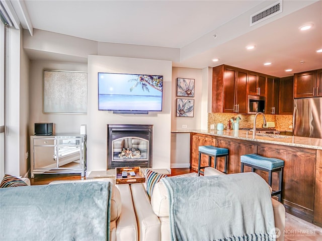 interior space featuring light stone counters, stainless steel appliances, visible vents, backsplash, and a sink