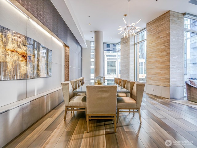 dining space with expansive windows, wood finish floors, and an inviting chandelier