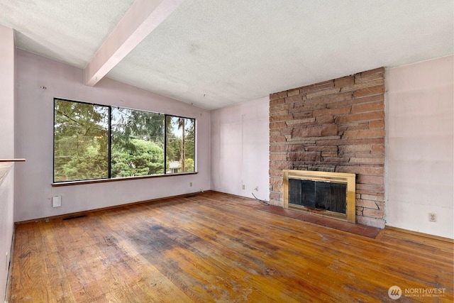 unfurnished living room with visible vents, hardwood / wood-style flooring, lofted ceiling with beams, a textured ceiling, and a fireplace