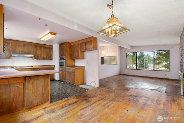 kitchen with under cabinet range hood, stainless steel appliances, and brown cabinets