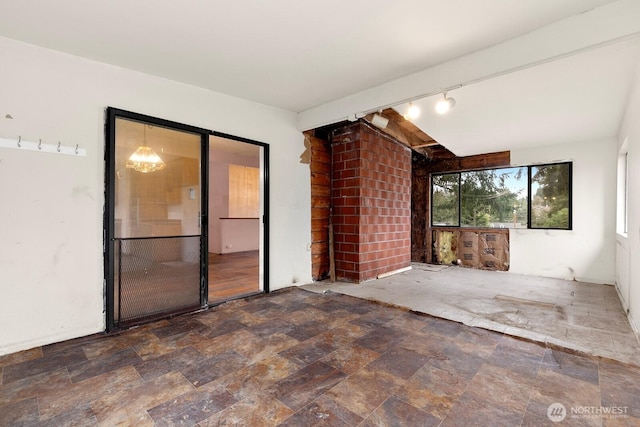 unfurnished room with rail lighting and stone finish floor