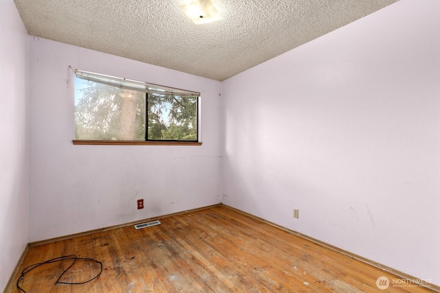 spare room with hardwood / wood-style flooring, visible vents, and a textured ceiling