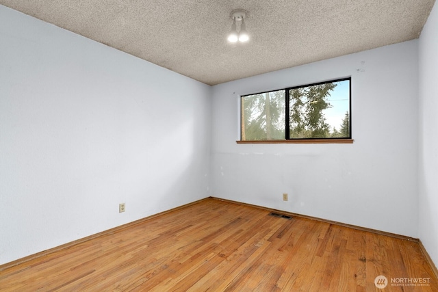 spare room featuring visible vents, a textured ceiling, and hardwood / wood-style floors