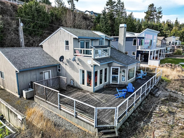 back of property featuring central air condition unit, a balcony, a shingled roof, and a deck