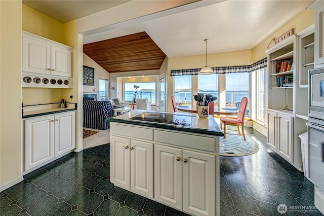 kitchen featuring dark countertops, lofted ceiling, white cabinetry, and a center island