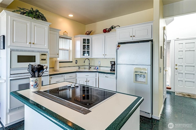 kitchen featuring glass insert cabinets, white appliances, white cabinets, and a sink