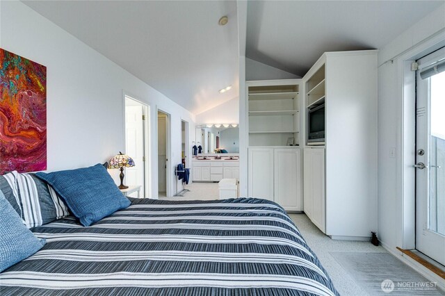 bedroom featuring ensuite bath, vaulted ceiling, and light colored carpet