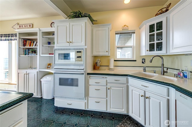 kitchen with glass insert cabinets, white appliances, white cabinetry, and a sink