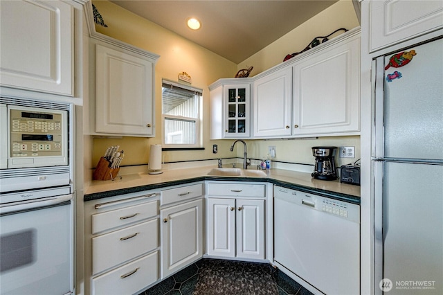 kitchen with white appliances, white cabinets, glass insert cabinets, a sink, and recessed lighting