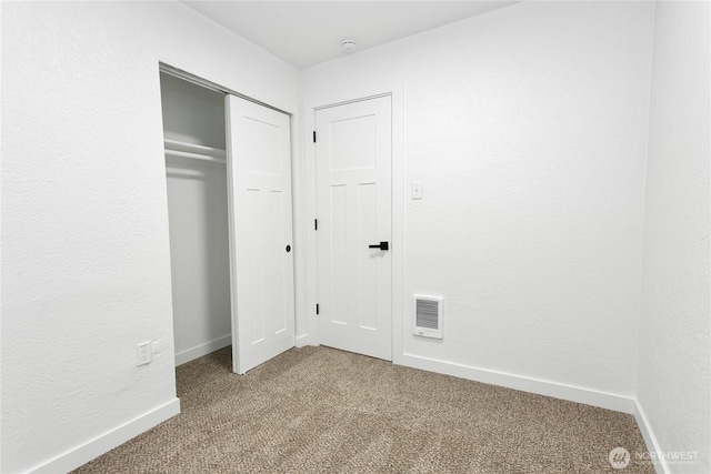 unfurnished bedroom with a closet, light colored carpet, visible vents, and baseboards