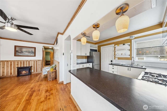 kitchen featuring sink, white cabinetry, hanging light fixtures, ornamental molding, and stainless steel fridge