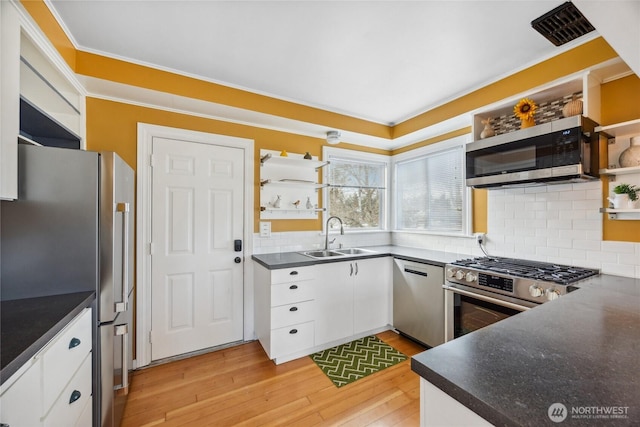 kitchen featuring sink, stainless steel appliances, tasteful backsplash, light hardwood / wood-style floors, and white cabinets