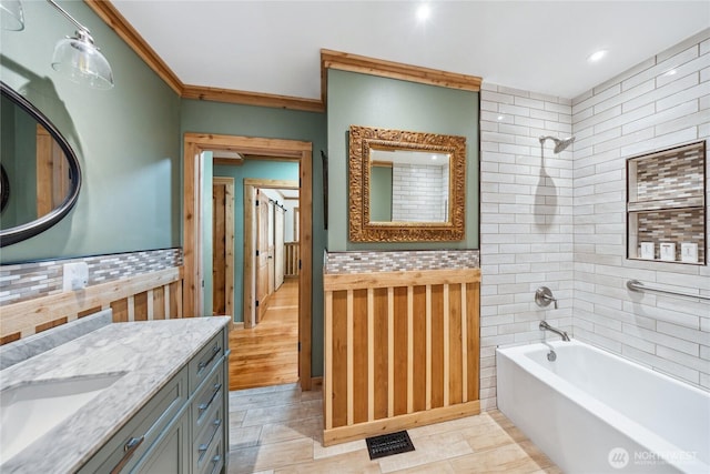 bathroom featuring tiled shower / bath combo, vanity, ornamental molding, and tile walls