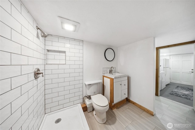 bathroom with vanity, toilet, and tiled shower