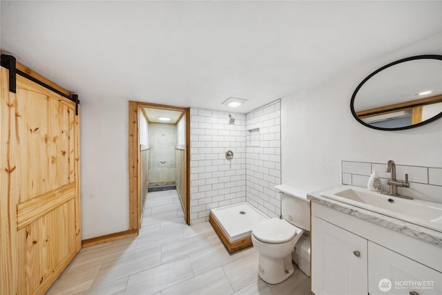 bathroom featuring vanity, toilet, and tiled shower