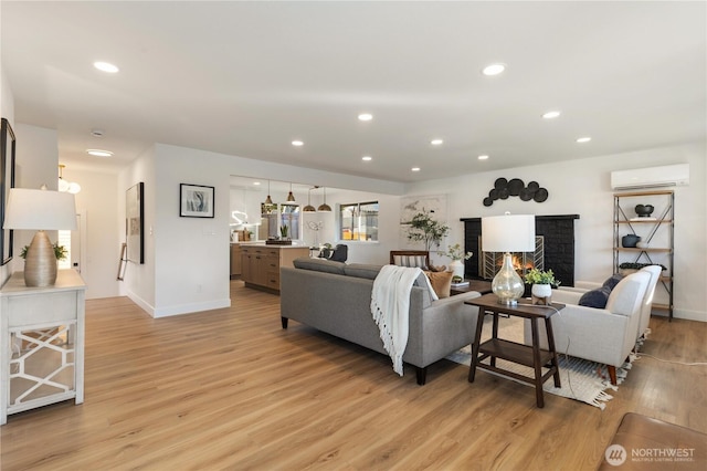 living area featuring baseboards, light wood finished floors, a wall unit AC, and recessed lighting