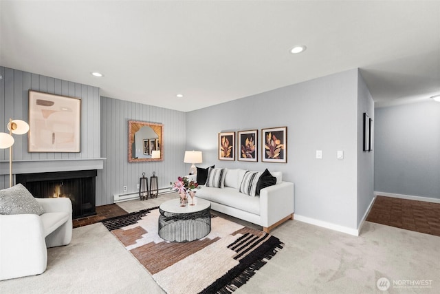 living room featuring a baseboard radiator, light colored carpet, and a large fireplace