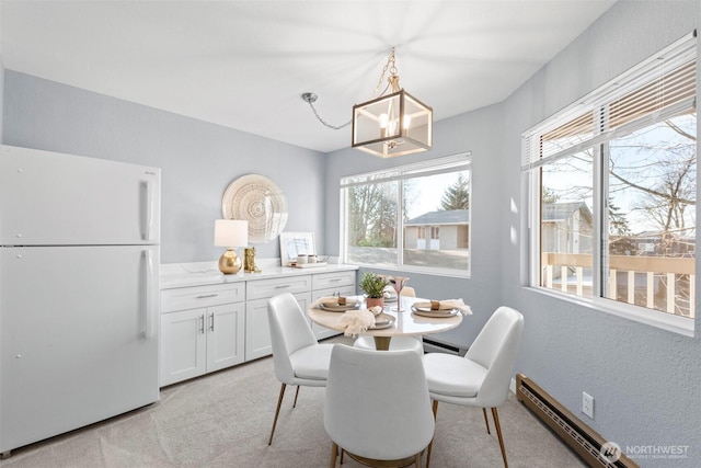 dining space featuring a baseboard heating unit, light colored carpet, and a chandelier