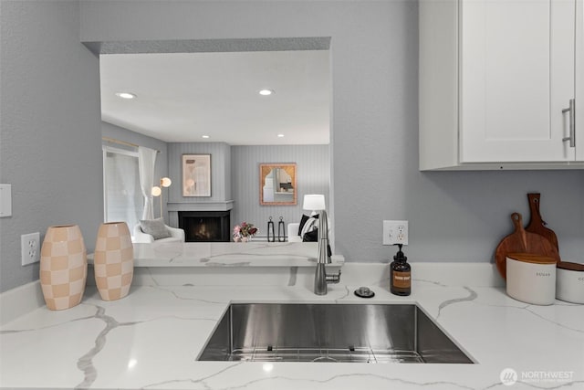 kitchen featuring white cabinetry, sink, and light stone countertops