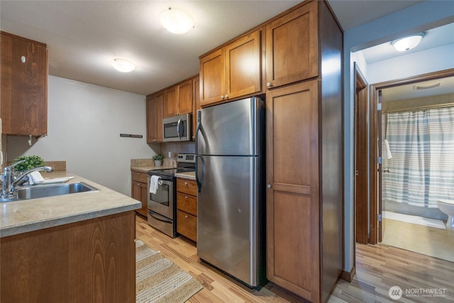 kitchen with sink, stainless steel appliances, and light wood-type flooring