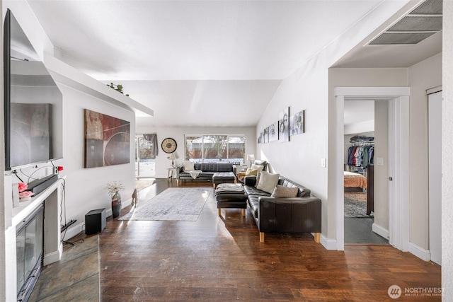 living room with vaulted ceiling, wood finished floors, visible vents, and baseboards