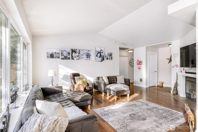 living room with lofted ceiling, a glass covered fireplace, wood finished floors, and baseboards