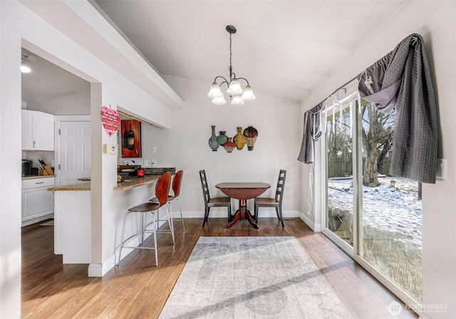 dining space featuring lofted ceiling, baseboards, an inviting chandelier, and wood finished floors